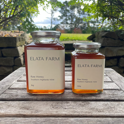 Two jars of Elata Farm honey on a wooden table with a natural background.